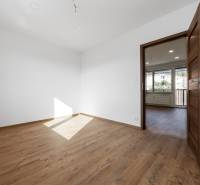 Szoba fa dekorációs padlóval és fehér falakkal egy háromszobás lakásban.