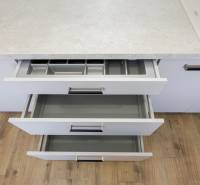 Háromszobás lakás konyhai fiókjainak kinyitása fa dekoros munkalappal és padlóval.