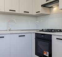 3 szobás lakás konyhája tűzhellyel és fehér szekrényekkel.