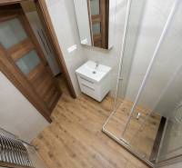 Fürdőszoba káddal, mosdóval és fa mintázatú padlóval egy háromszobás lakásban.