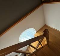 Fa dekorációjú lépcső egy családi házban, lépcsőkorláttal és körablakkal.