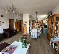 Nappali konyhával családi házban, fa dekoros padló, virágok az asztalon.