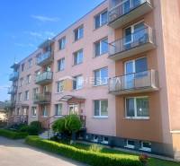 Négyemeletes társasház Moravské Lieskovóban, erkélyekkel és parkolóval az épület előtt.