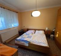 Hálószoba családi házban két ággyal, szekrénnyel és szőnyeggel.