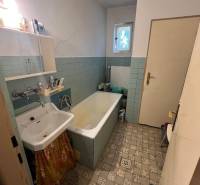 Fürdőszoba egy családi házban régi káddal, mosdóval és csempével.