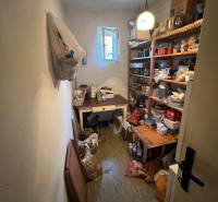 Családi ház tárolóhelyisége polcokkal, amelyek tele vannak különféle tárgyakkal és nyitott ablakkal.