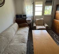 Nappali egy családi házban kanapéval, fotellel és fa bútorokkal.