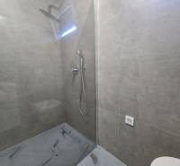 Átlátszó paravános zuhanykabin szürke csempékkel a villában.