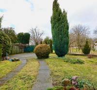 A Kalinčiaka utcai családi ház kertje Michalovcében, járdával és fákkal.