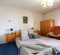 Hálószoba nagy ággyal, fa szekrényekkel és székkel egy családi házban.