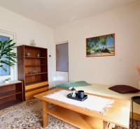 Nappali egy családi házban szőnyegpadlóval, fa bútorokkal és egy tengerparti képpel.