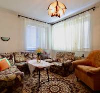 Nappali egy családi házban kényelmes kárpitozott bútorokkal és díszes szőnyeggel.