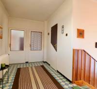 Családi ház mintás burkolattal, fa lépcsőkkel és egyszerű faldekorációval.