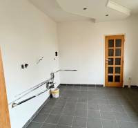 Üres szoba egy kétszobás lakásban, sötét csempézett padló, fehér falak, faajtók.