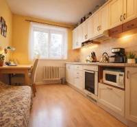 Konyha egy kétszobás lakásban, fa dekor padlóval, világos bútorokkal és étkező sarokkal.