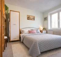 Hálószoba egy kétszobás lakásban nagy ággyal, dekorációkkal és természetes megvilágítással.