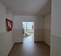 Folyosó fehér falakkal és világos csempével egy háromszobás lakásban.