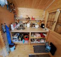 Fa konyha készülékekkel, polcokkal és mosogatóval a kert belsejében.