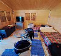 Szoba a kertekben asztallal, székekkel és két ággyal színes takarókkal.