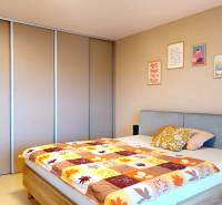 Hálószoba családi házban ággyal, beépített szekrénnyel és dekoratív képekkel a falon.