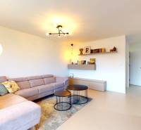 Nappali egy családi házban sarokkanapéval, kerek asztalokkal és fa dekorációjú padlóval.