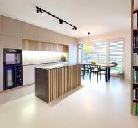 Nyitott konyha étkezőasztallal és könyvespolccal egy családi házban.