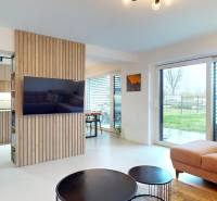 Nappali nagy ablakokkal, kényelmes kanapéval és fa dekorációval a falon.