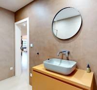 Fürdőszoba egy családi házban mosdóval, kerek tükörrel és zuhanyzóval.