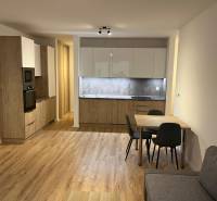 Konyha egy kétszobás lakásban fa dekorációjú padlóval és étkezőasztallal.