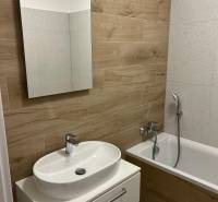 Fürdőszoba egy kétszobás lakásban, fa dekor padlóval és káddal.