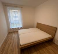 Hálószoba ággyal, fa dekoros padlóval egy kétszobás lakásban.