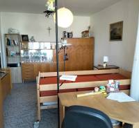 Szoba egy kétszobás lakásban bútorokkal, ággyal és dekorációkkal a polcokon.