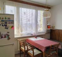 Konyha egy kétszobás lakásban étkezőasztallal, székekkel és hűtőszekrénnyel, amelyen mágnesek vannak.