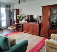 Nappali egy kétszobás lakásban, fa hatású padlóval és kényelmes bútorokkal.