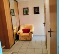 Szék a bejárati ajtónál csempézett padlóval egy kétszobás lakásban, tükrös szekrény.