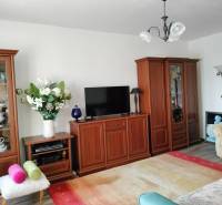 Nappali egy kétszobás lakásban, fa dekorációval és világos belső térrel.