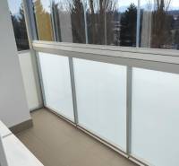 Üvegezett erkély egy kétszobás lakásban, kilátással a fákra és a hegyekre.