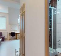 Iroda sarokkanapéval, asztallal, zuhanyzóval és falon lévő fa dekorációval.