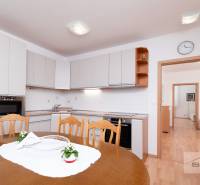 Ebédlő egy 3 szobás lakásban konyhabútorral és fa dekorációjú padlóval.