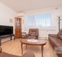 Nappali egy háromszobás lakásban bőr bútorokkal és fa dekorációjú padlóval.