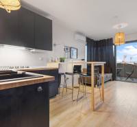 Konyha fekete szekrényekkel, bárpulttal és fa dekorációjú padlóval egy egyszobás lakásban.