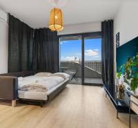 Nappali rész egy egyszobás lakásban ággyal, fa dekoros padlóval és erkéllyel.