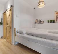 Hálószoba egy egyszobás lakásban tolóajtókkal és fa dekorációjú padlóval.