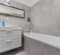 Fürdőszoba káddal, mosdóval és tükörrel egy egyszobás lakásban.