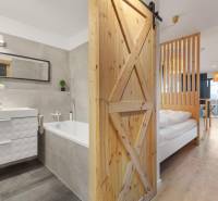 1 szobás lakás belső tere káddal és fa dekorációjú padlóval.