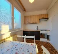 Konyha egy kétszobás lakásban, fa dekorációjú padlóval és étkezőasztallal.