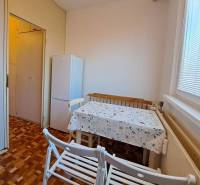 Ebédlő egy kétszobás lakásban, fa dekoros padlóval és fehér hűtőszekrénnyel.