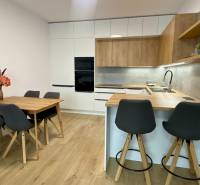 Konyha egy kétszobás lakásban, fa dekoros padlóval, étkezőasztallal és bárpulttal.