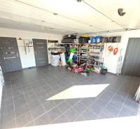 Családi ház garázsa szerszámokkal és tároló polcokkal, kerámia csempével burkolt padló.