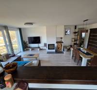 Nappali egy családi házban kanapéval, televízióval és étkezőasztallal, fa dekor padlón.